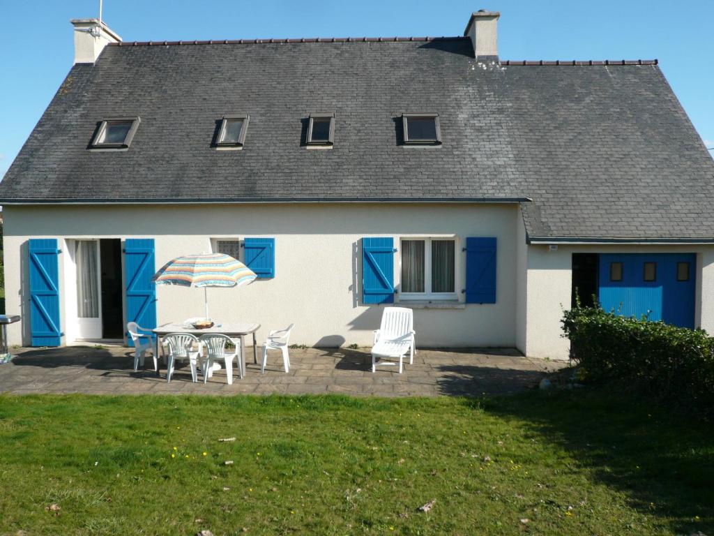 a white house with blue doors and a table and chairs at les volets bleus in Camaret-sur-Mer