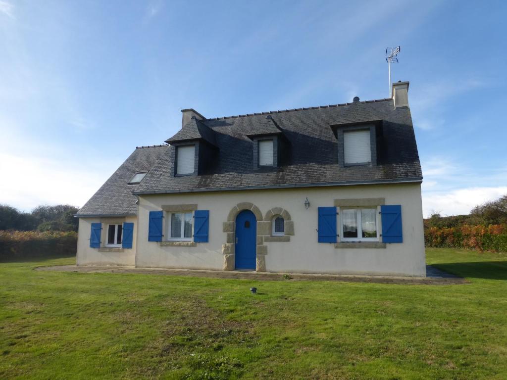 a house with a blue door on a grass field at les volets bleus in Camaret-sur-Mer