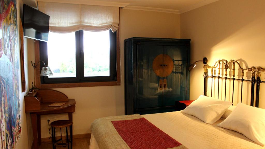 a bedroom with a bed and a window and a table at Apartamento Spellos in Rosal