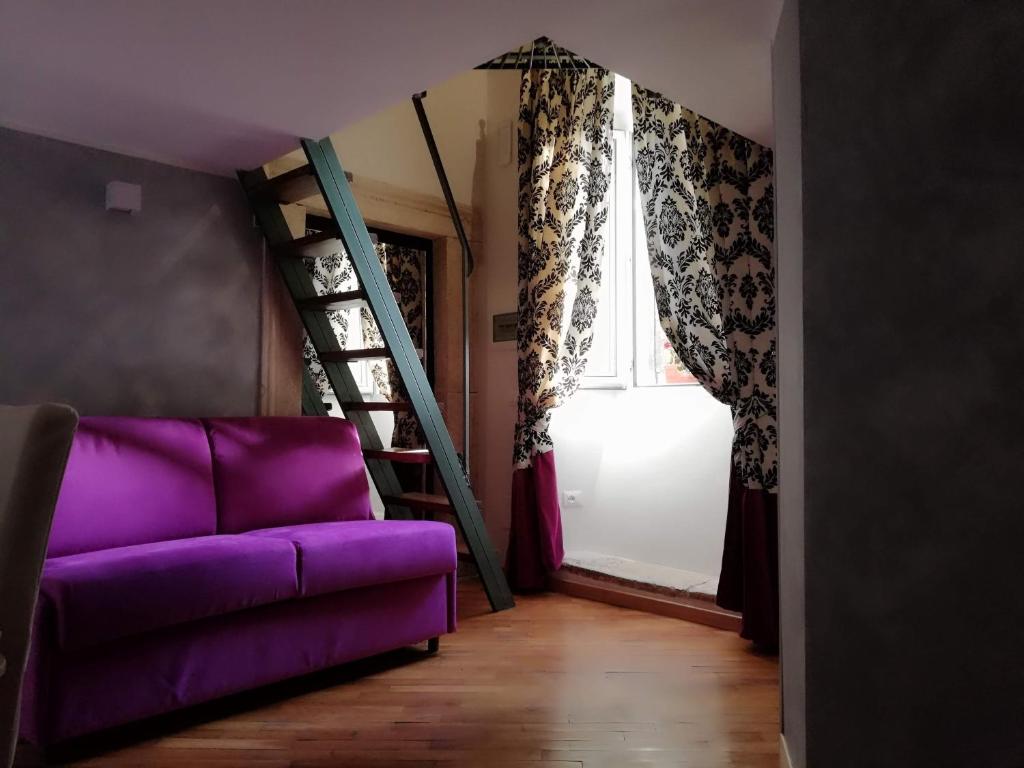 um sofá roxo sentado num quarto com uma escada em Cà Ro - Casa Rosetta "Tiny house" em Tivoli