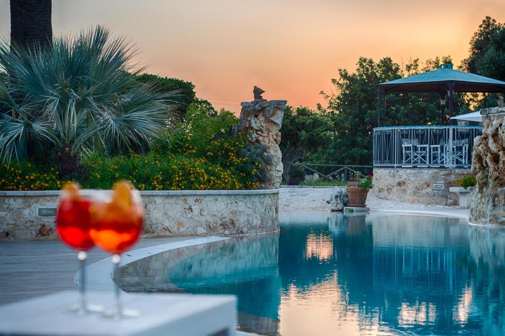 a wine glass sitting on a table next to a swimming pool at Masseria Valente in Ostuni