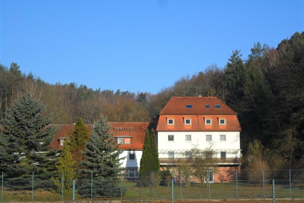 une grande maison blanche avec un toit rouge dans l'établissement Hotel Badstube, à Otterberg
