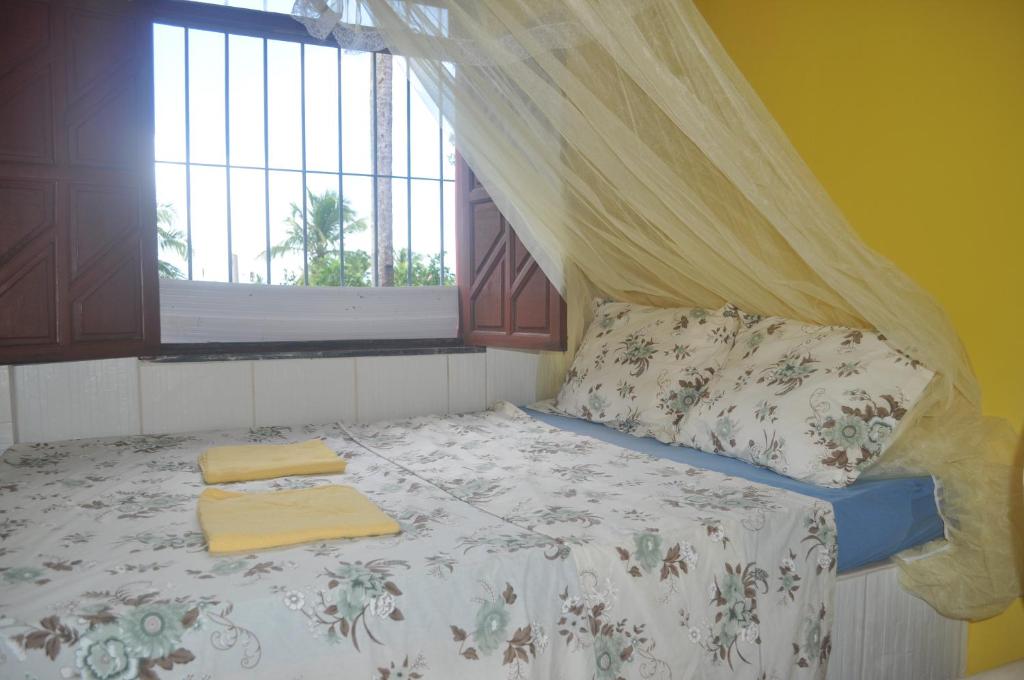 um quarto com uma cama com uma janela e toalhas em Sitio Os Tres em Camaçari