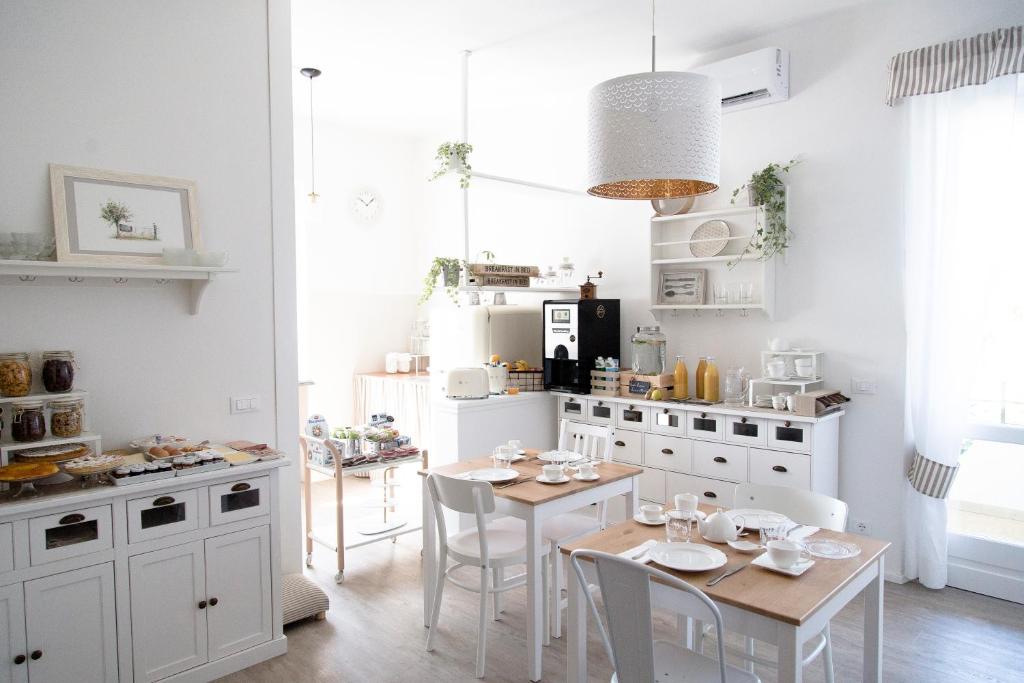 cocina con armarios blancos, mesa y sillas en aMarti Suites B&B, en Santo Stefano di Magra