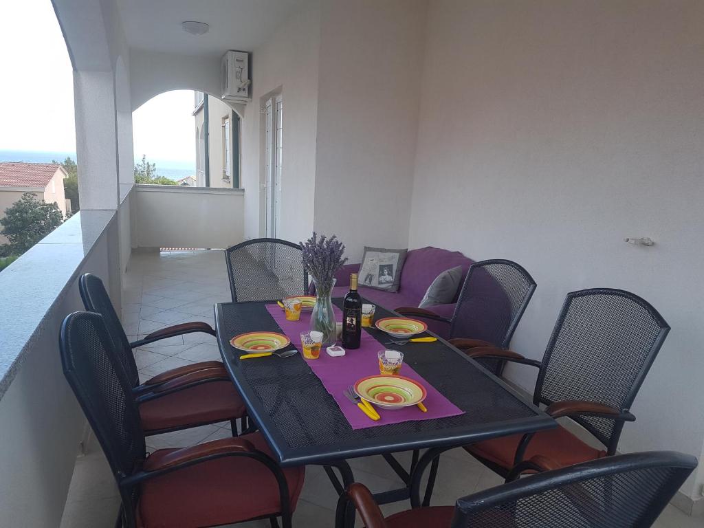 a dining room table with chairs and a table with yellow plates at Apartment Stiller in Novalja