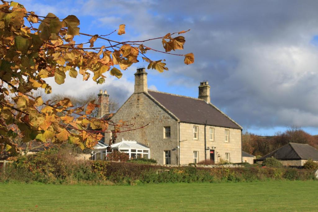 a large stone house with two chimneys at Thropton Demesne Farmhouse B&B in Rothbury