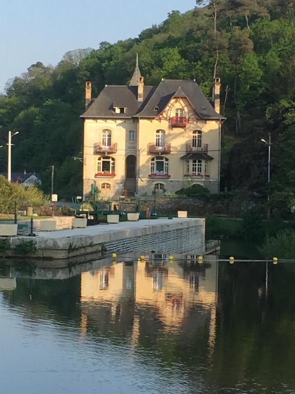 a large house sitting on the side of a body of water at Villa Tranquillité in Rohan