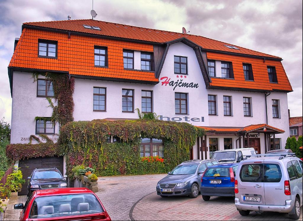 un gran edificio con coches estacionados frente a él en Hotel Hajčman en Žďár nad Sázavou