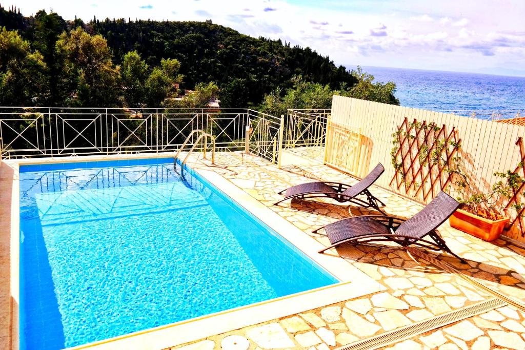 a swimming pool with two chairs and the ocean at Agios Nikitas View in Agios Nikitas