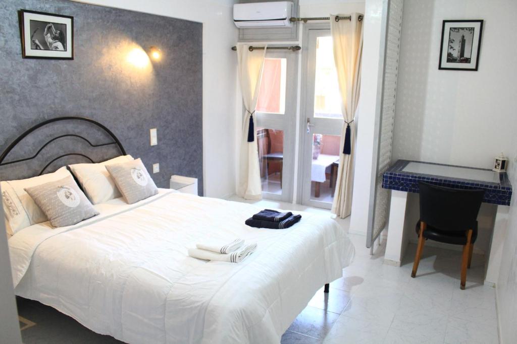 a bedroom with a white bed and a desk at El Hamra Hotel in Marrakech