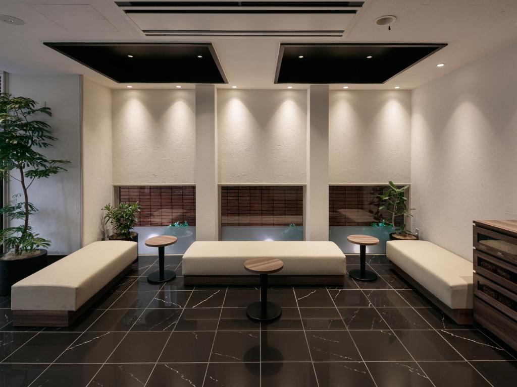 a waiting room with a couch and two stools at Hotel Mystays Kagoshima Tenmonkan Annex in Kagoshima