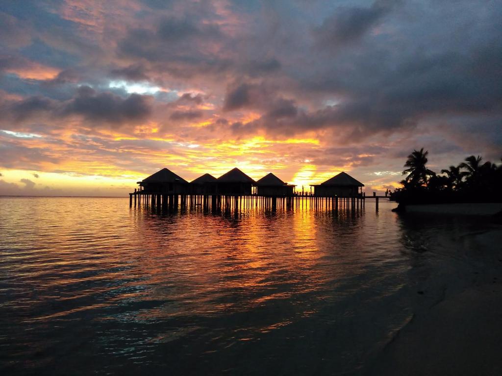 a group of huts on the water at sunset at Coconuts Beach Club Resort and Spa in Fausaga