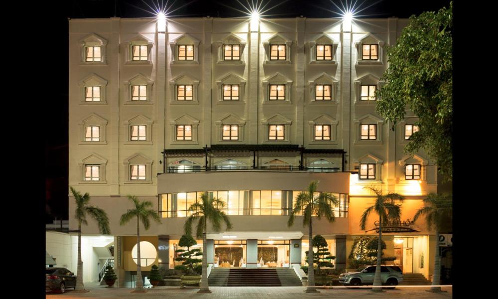 un gran edificio blanco con muchas ventanas por la noche en Chau Pho Hotel, en Chau Doc