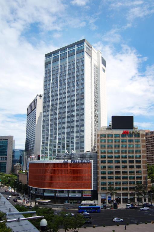 a tall white building in a city with a parking lot at Hotel President in Seoul