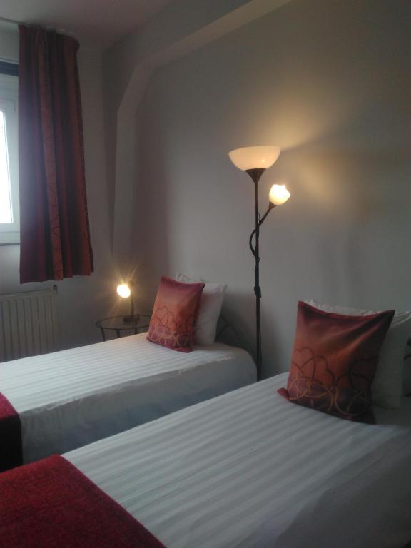 two beds with red pillows in a hotel room at Eurotel in Liège