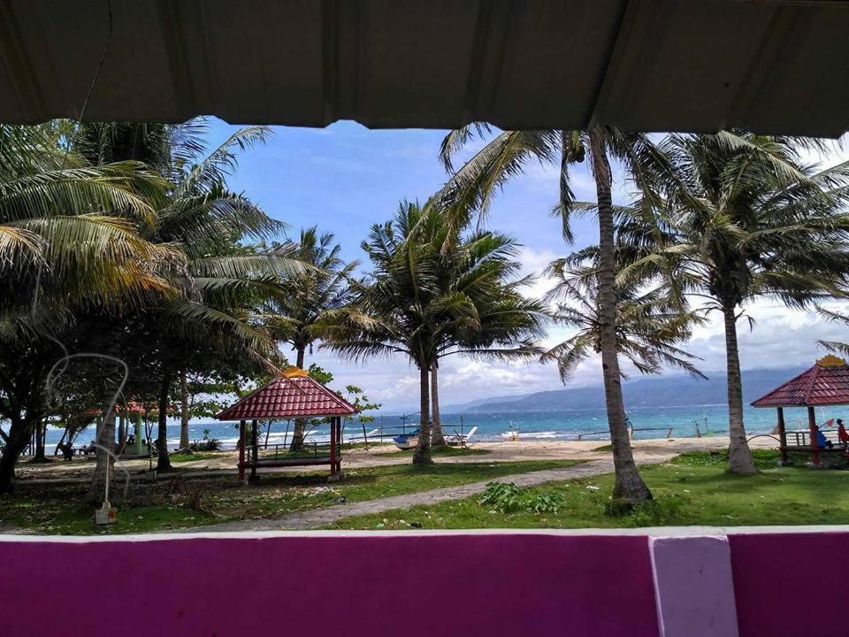 een uitzicht op een strand met palmbomen en de oceaan bij Hotel Sunset Beach labuhan jukung in Krui