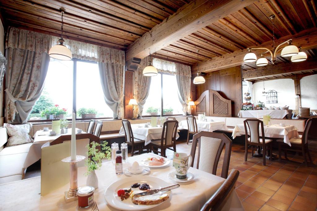 un comedor con mesas, sillas y ventanas en Bärnsteinhof - Gasthof mit Herz, en Aigen im Mühlkreis