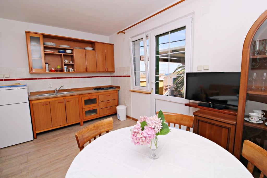 a kitchen with a table with a vase of flowers on it at Filipi Apartment in Sali