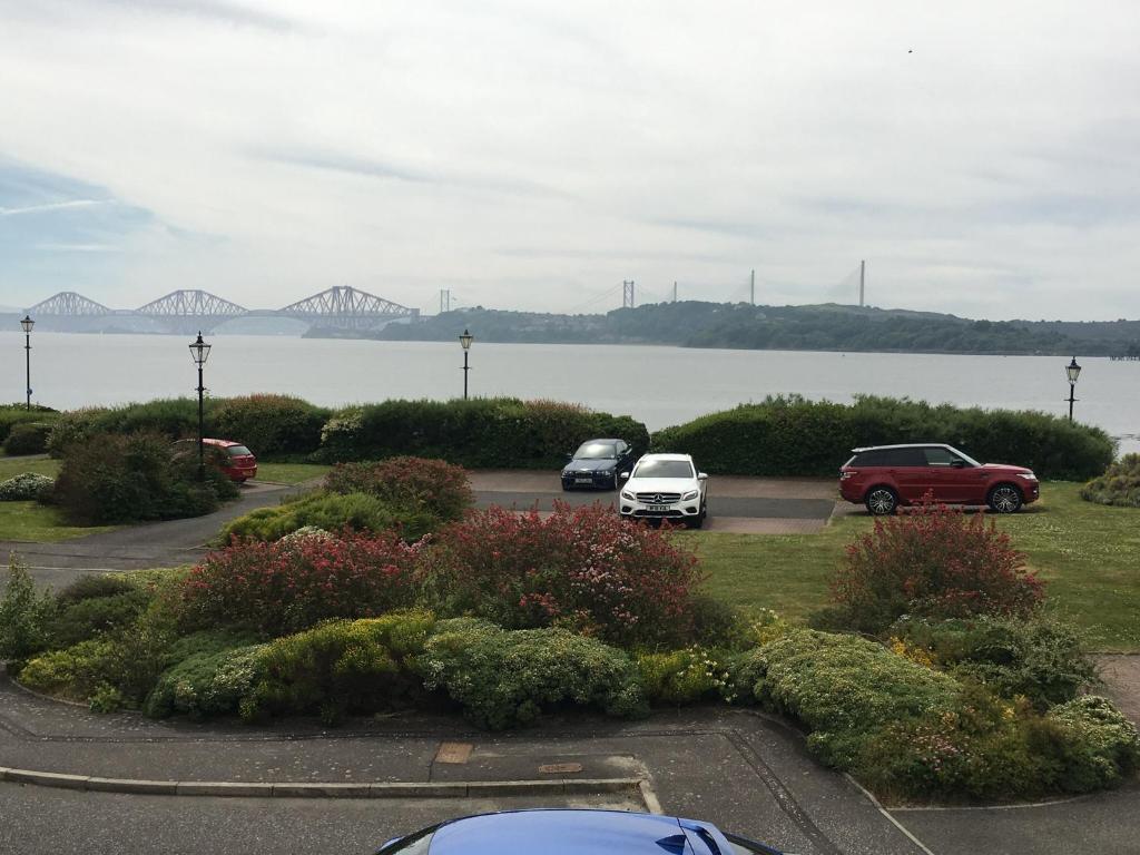 um grupo de carros estacionados num parque de estacionamento perto da água em Prime Dalgety Bay Waterfront Apartment em Saint Davids