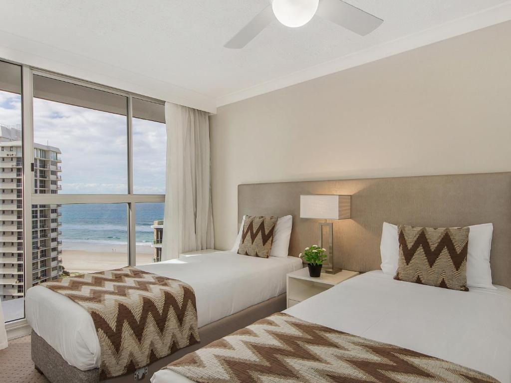 two beds in a room with a view of the ocean at Sunbird Beach Resort in Gold Coast