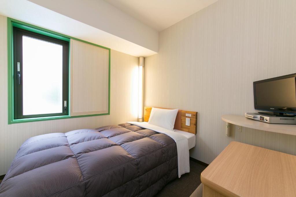 a hotel room with a bed and a flat screen tv at R&B Hotel Umeda East in Osaka