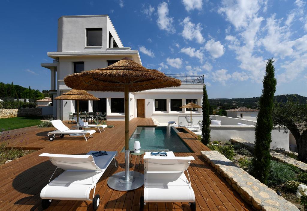 ヴィルヌーヴ・レ・ザヴィニョンにあるLes Loges En Provence "Villa 360"のスイミングプール、椅子2脚、パラソルが備わるヴィラです。