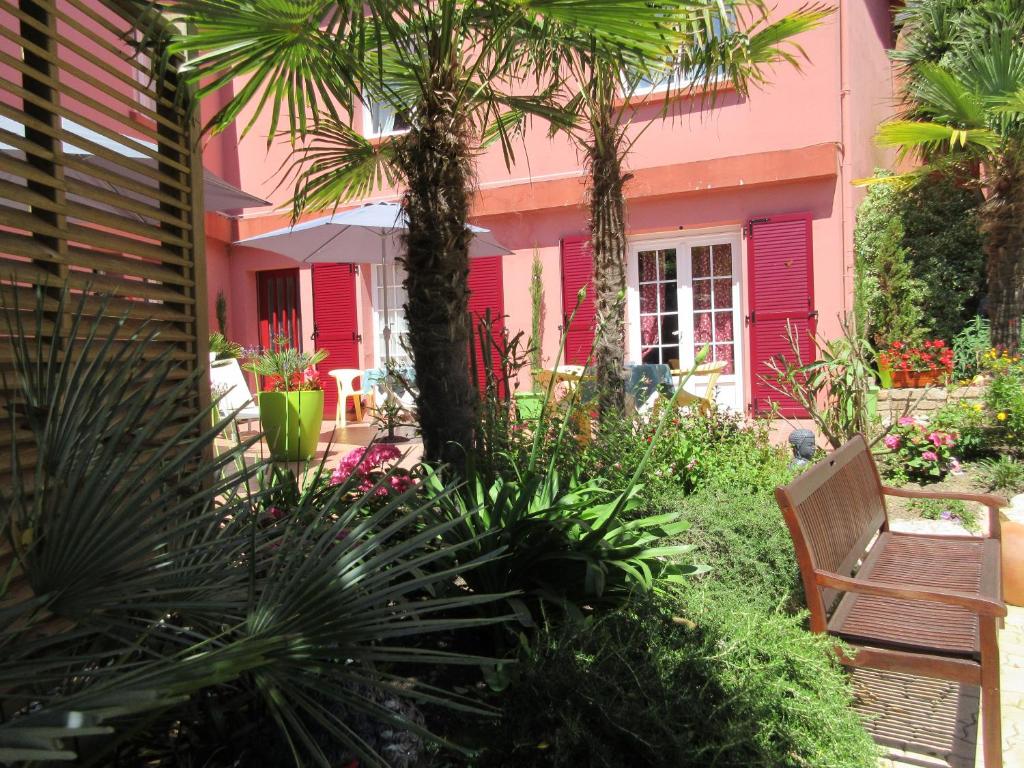 エテルにあるLe Trianonのベンチとヤシの木があるピンクの家