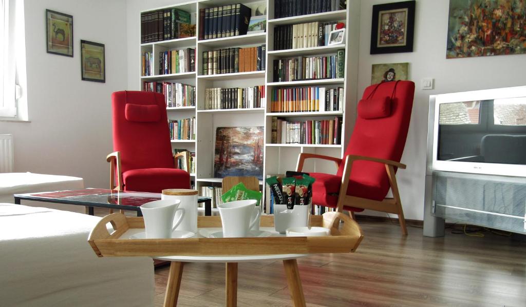 a living room with two red chairs and a coffee table at Apartment & Room Renee in Osijek