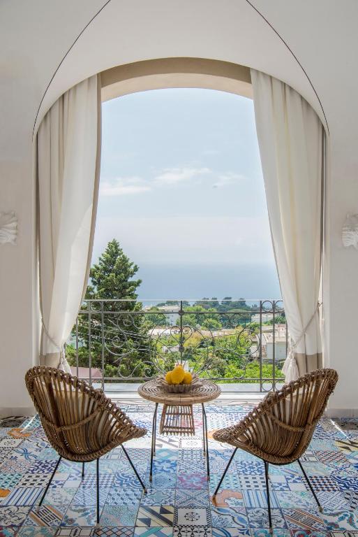 a room with two chairs and a table and a window at Capri Tiberio Palace - The Leading Hotels of the World in Capri