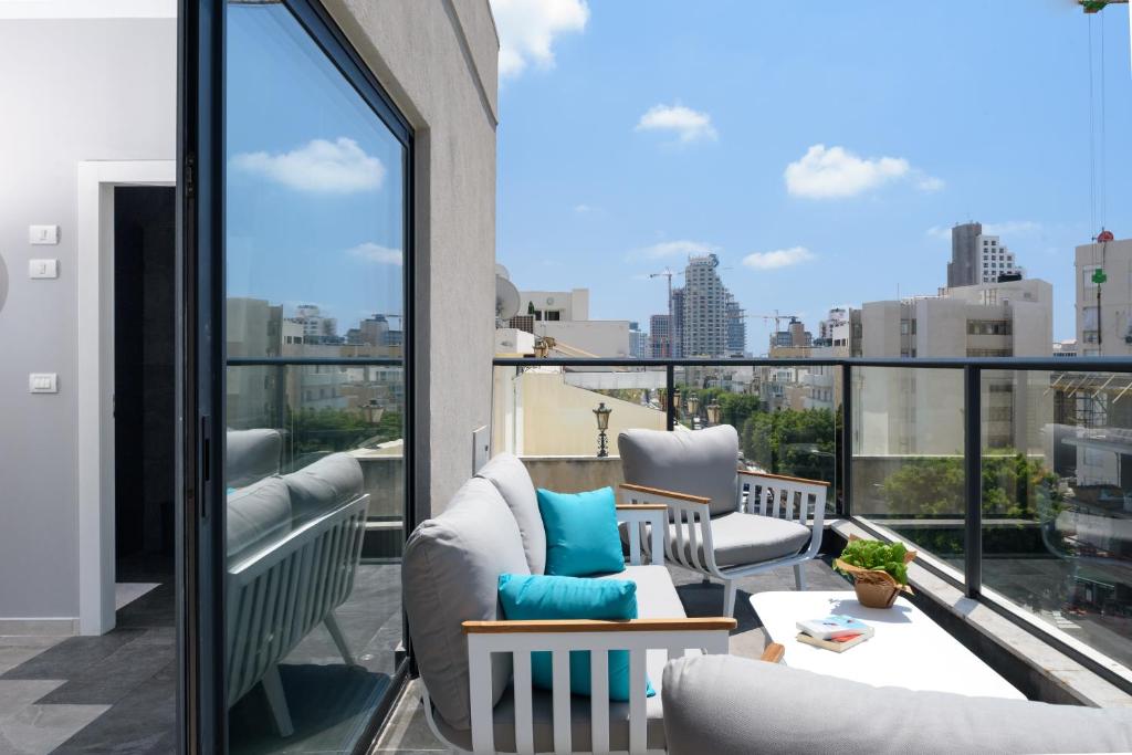 uma varanda com cadeiras e vista para a cidade em The Roof - By Sea Land Suites em Tel Aviv