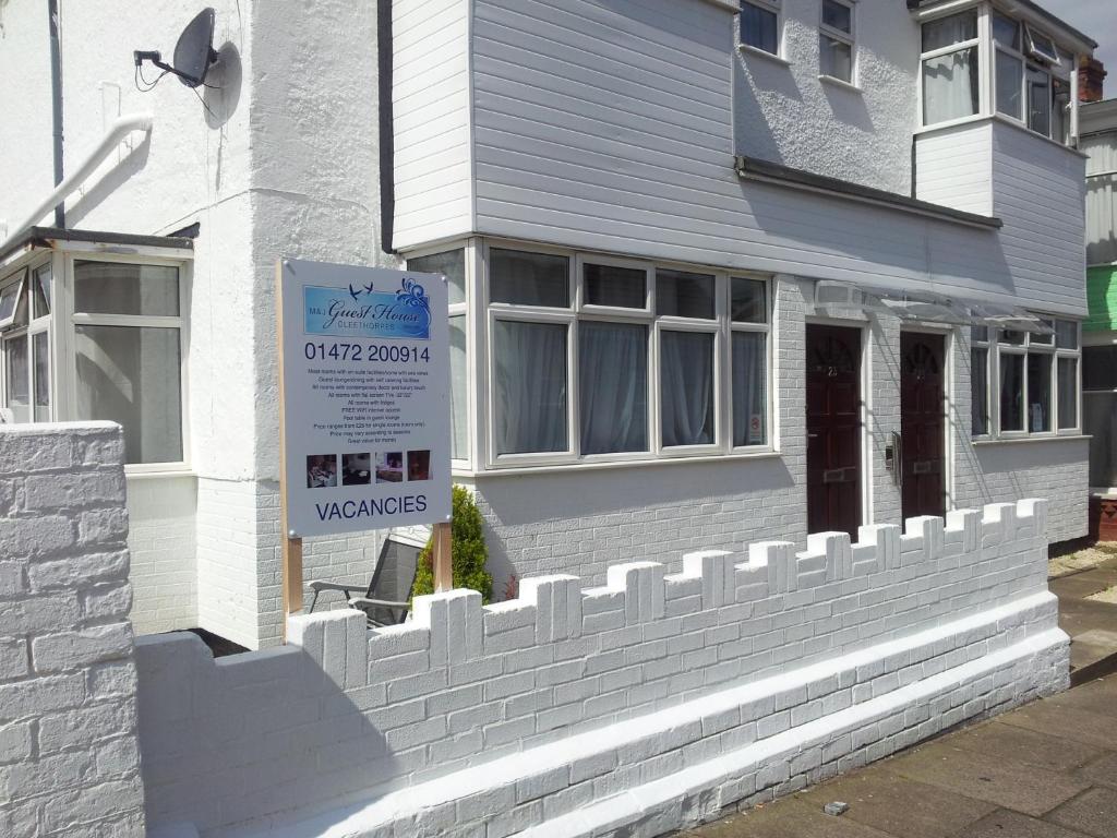 a white house with a sign in front of it at M and J Guest House in Cleethorpes