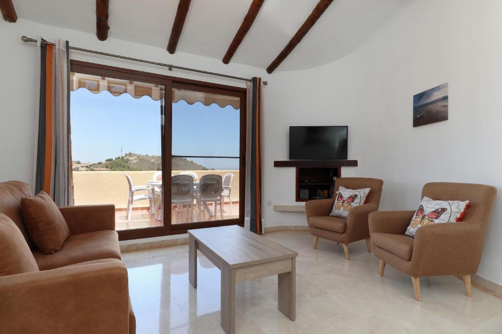 a living room with a couch and chairs and a television at Las Palmeras 4 with rooftop solarium and fiber optic internet in Atamaría