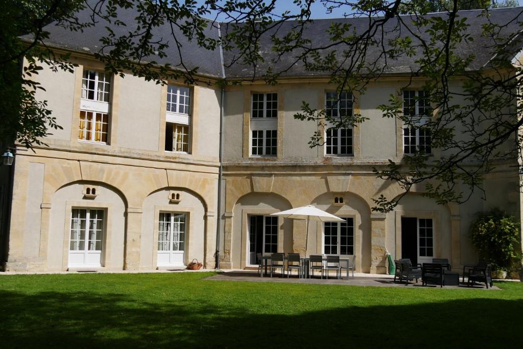 ein großes Gebäude mit Rasen davor in der Unterkunft Magnifique château rénové proche bourg grand parc belle terrasse billard, ping pong, proche Bayeux et plages du débarquement in Tilly-sur-Seulles