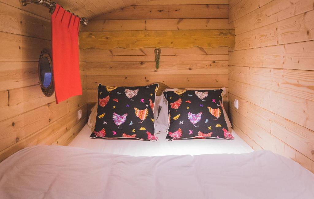 a bed in a wooden cabin with two pillows at L&#39;Escale des Châteaux de la Loire in Angé