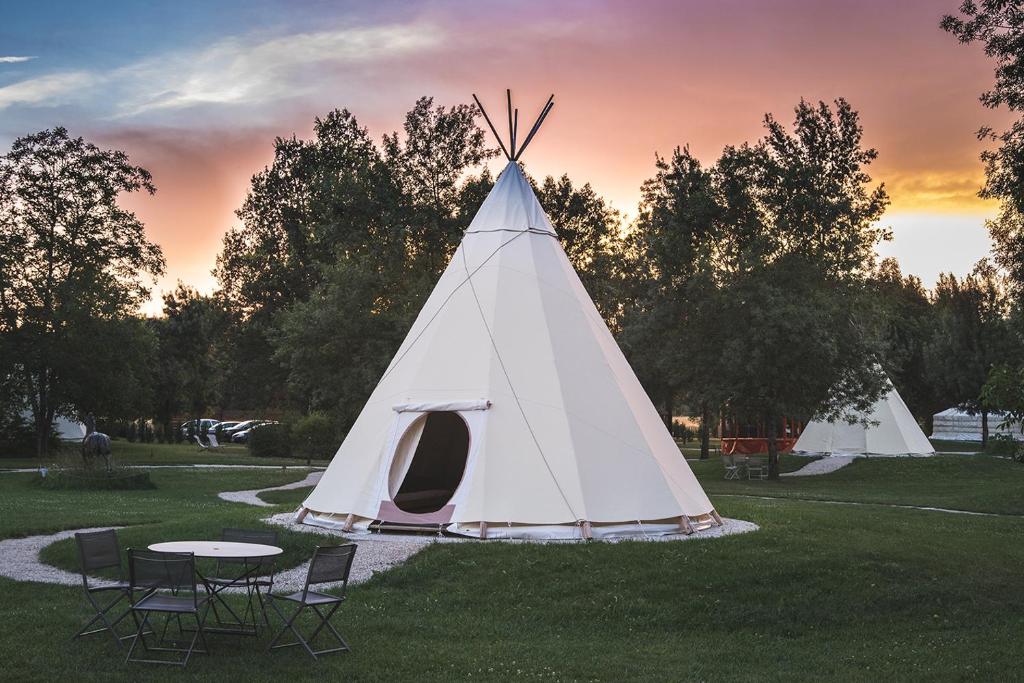 a white teepee tent with a table and chairs at L&#39;Escale des Châteaux de la Loire in Angé