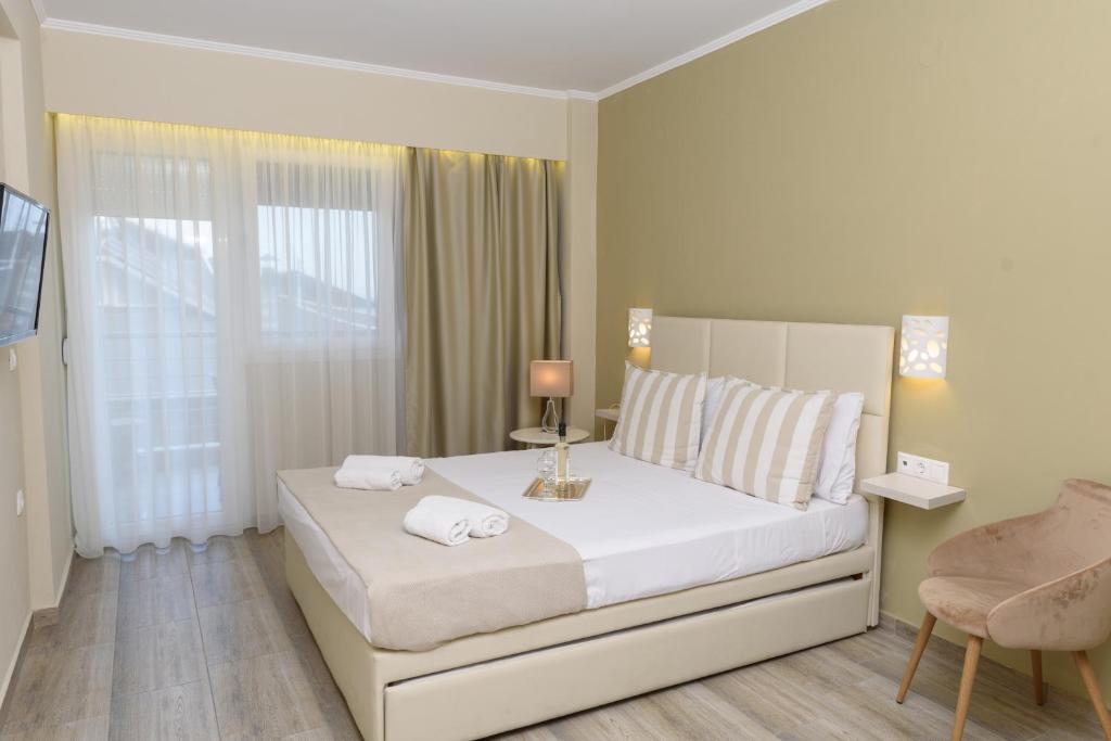 a white bedroom with a bed with towels on it at Ammos Beach Seaside Luxury Suites Hotel in Olympic Beach