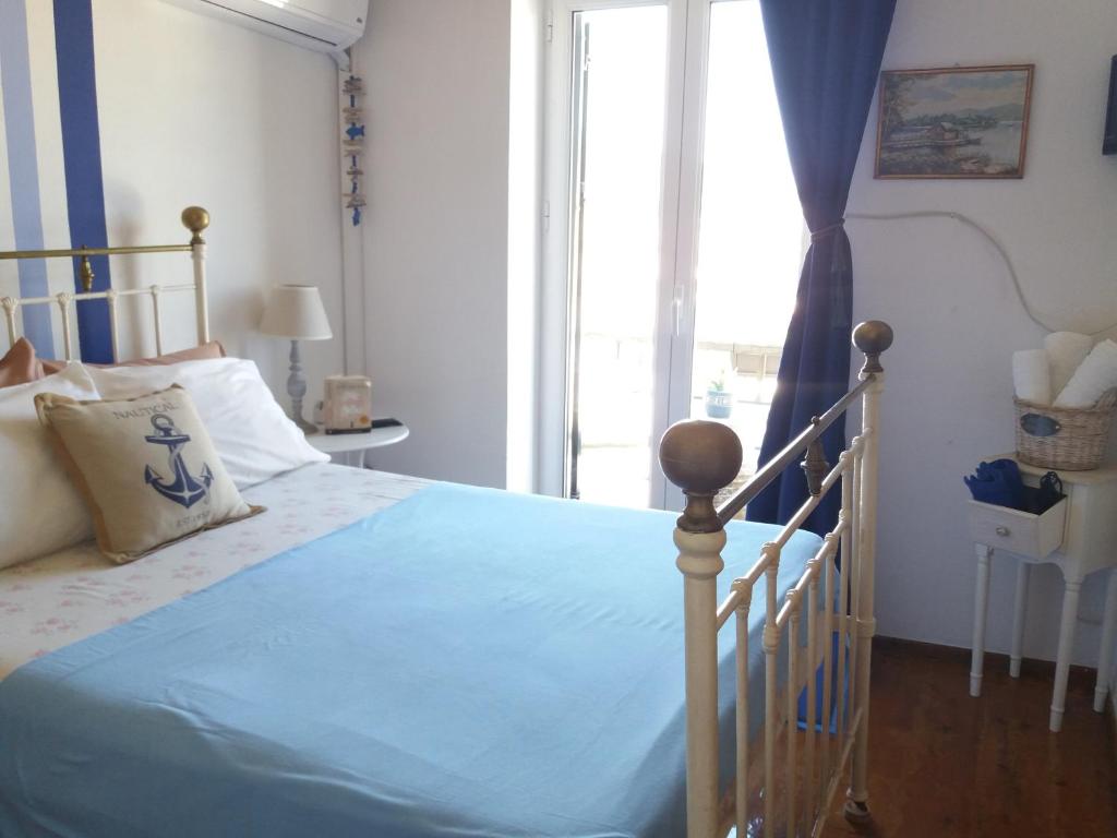 a bedroom with a bed with blue sheets and a window at Water Planet Rooms in Gaios