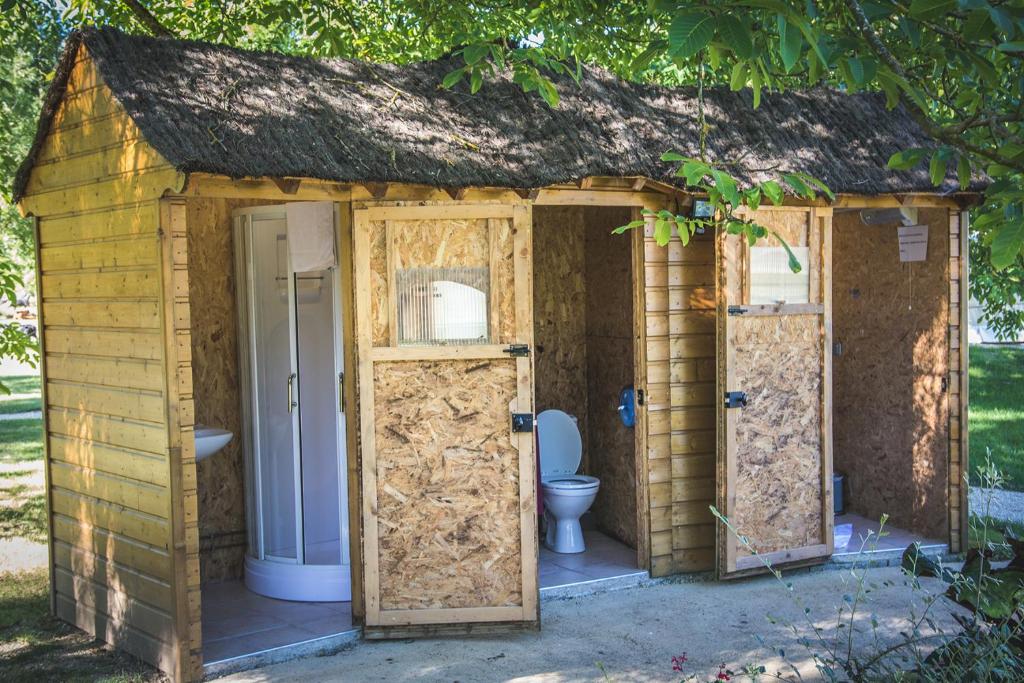 a wooden shed with three doors and a toilet at L&#39;Escale des Châteaux de la Loire in Angé