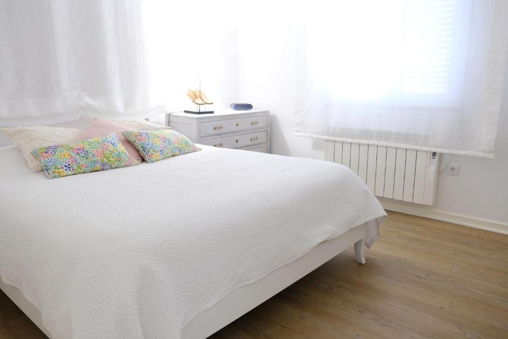 Elle comprend un lit blanc avec des draps et des oreillers blancs ainsi qu'une fenêtre. dans l'établissement Vale Coelhos Casa de Campo, à Sarnadela