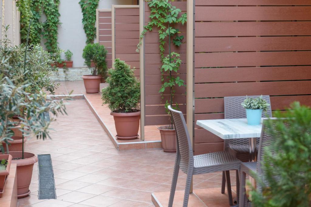 a patio with a table and chairs and potted plants at Ammos Beach Seaside Luxury Suites Hotel in Olympic Beach