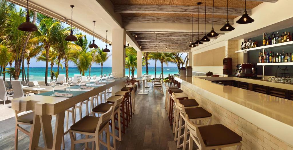 een restaurant met een bar met de oceaan op de achtergrond bij Catalonia Royal Tulum Beach & Spa Resort Adults Only - All Inclusive in Xpu Ha