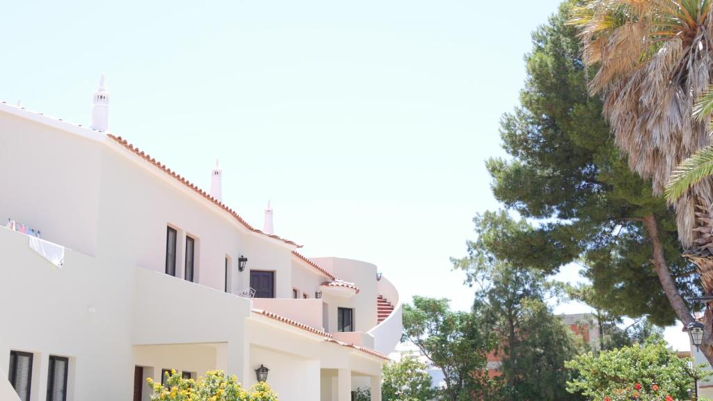 un bâtiment blanc avec des arbres devant lui dans l'établissement Casas da Praia, à Manta Rota