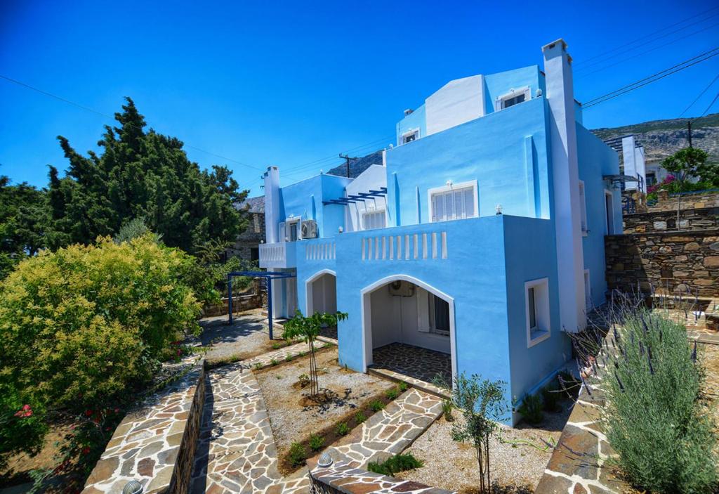 a large blue house with trees in front of it at Peskesi Ikaria in Agios Kirykos