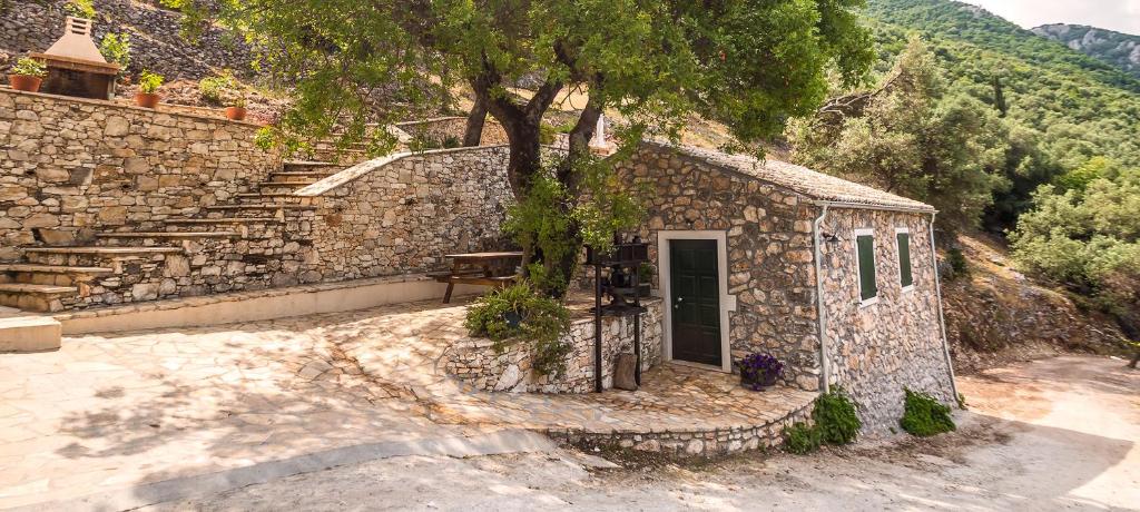 a small stone building with a tree and stairs at Castelli Olive Press in Acharavi