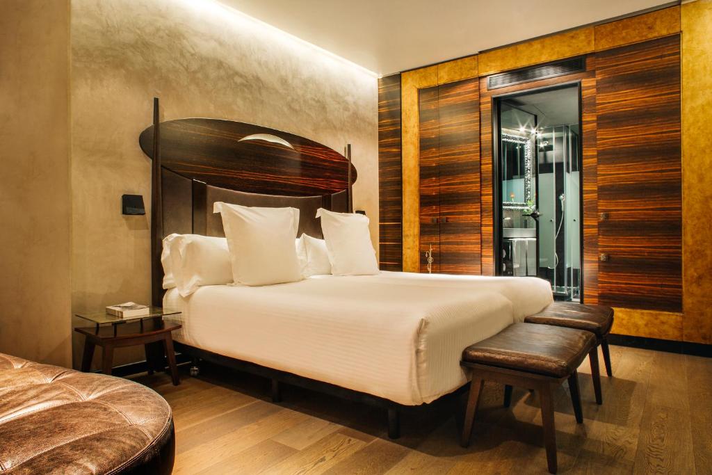 a bedroom with a large bed with a wooden headboard at Hotel Bagués, a Small Luxury Hotel of the World in Barcelona
