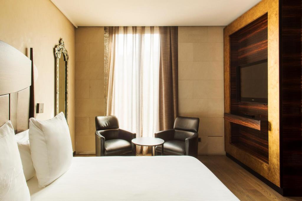 a hotel room with a bed and two chairs at Hotel Bagués, a Small Luxury Hotel of the World in Barcelona