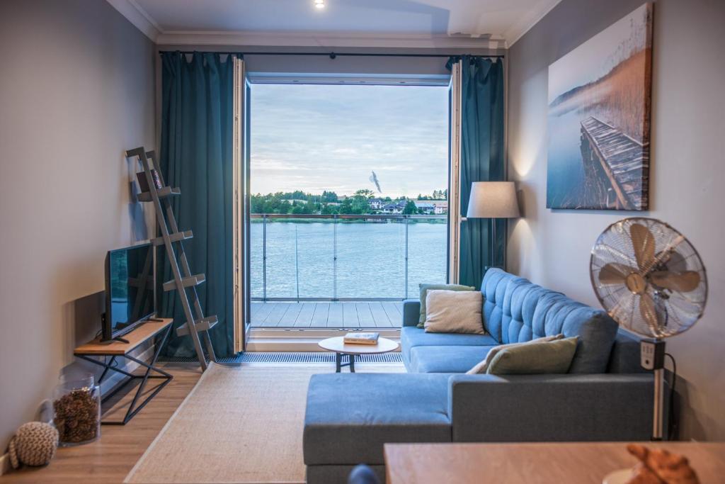 salon z niebieską kanapą i dużym oknem w obiekcie Apartament Villa Nautica w Rydzewie
