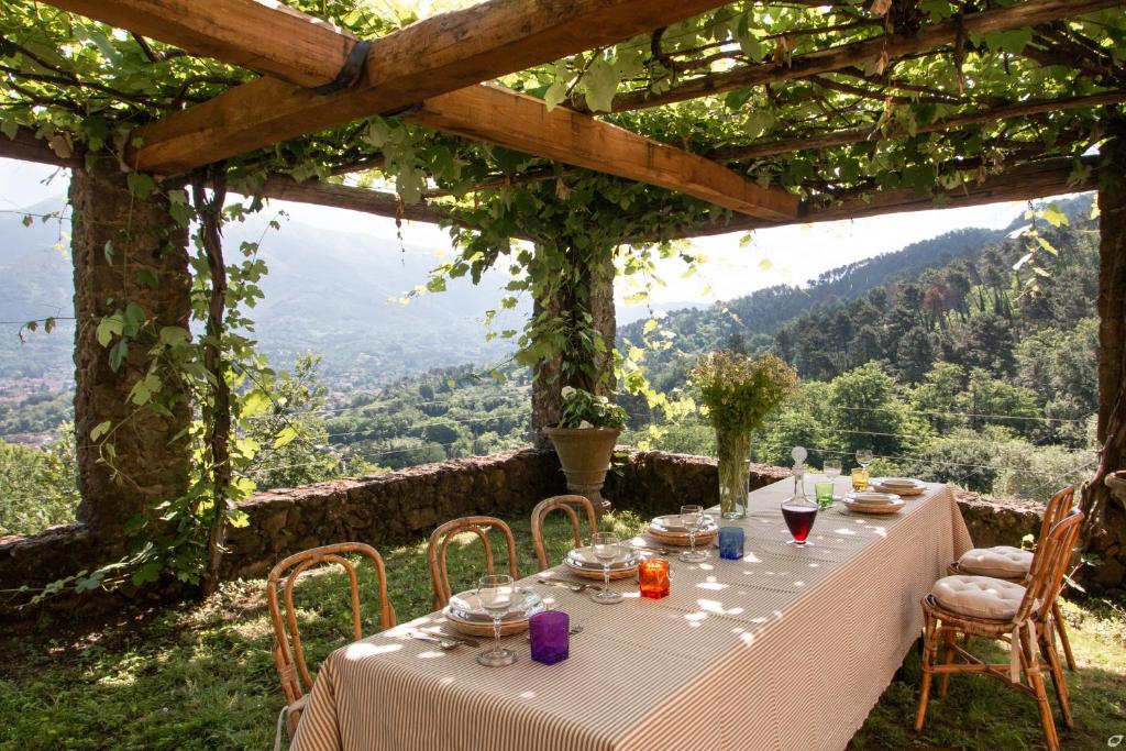 a table set up for a meal under a pergola at Villa Doriana in Camaiore