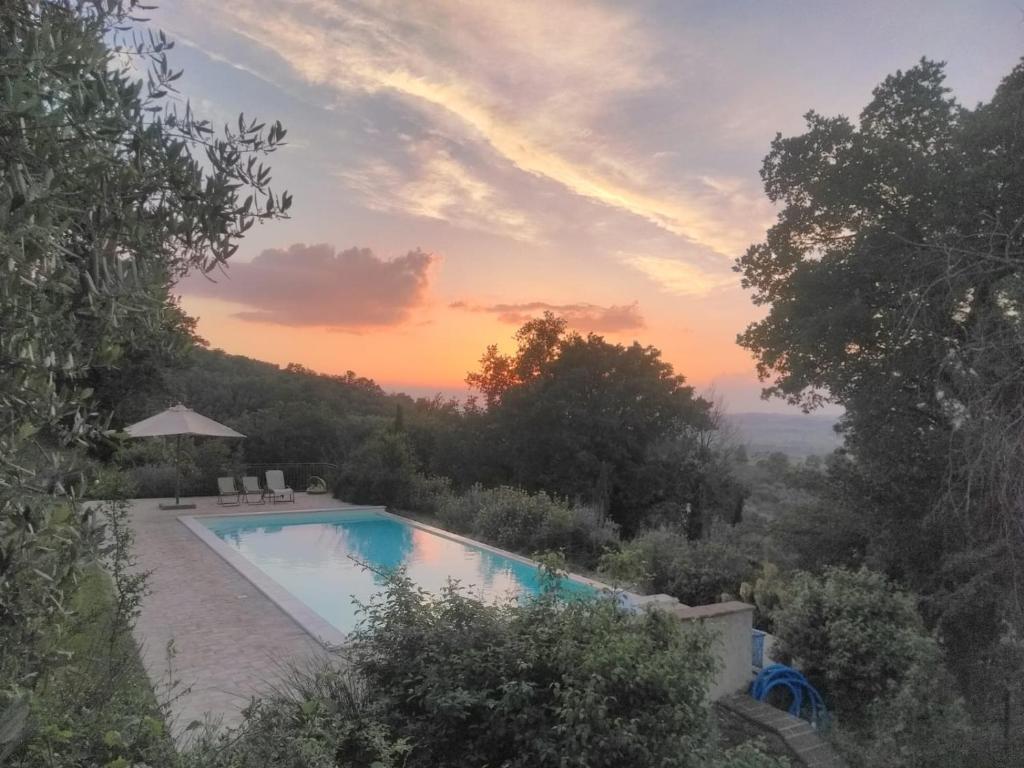una piscina con puesta de sol en el fondo en Fonte Pace Luxury Villa - a Fontanaro Property, en Paciano