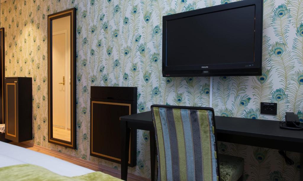 a flat screen tv hanging on a wall with a chair at Thon Hotel Opera in Oslo